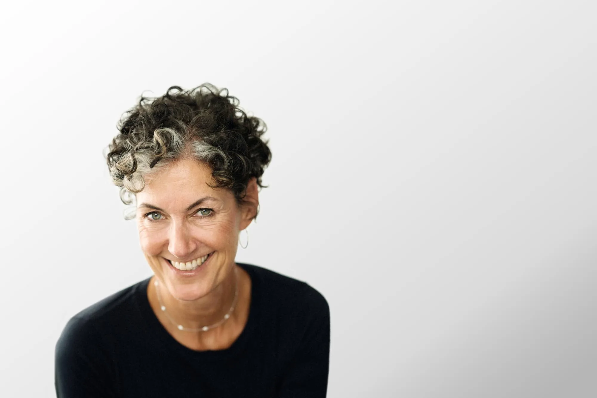 Nancy Giordano smiling, photographed against a light studio backdrop